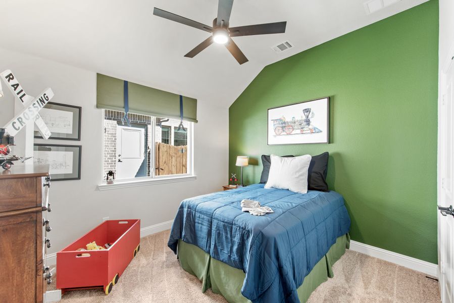 Child's bedroom with green accent wall, vaulted ceiling, ceiling fan, and train-themed decor Child's bedroom with green accent wall, vaulted ceiling, ceiling fan, and train-themed decor