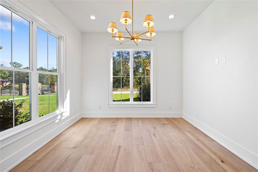 Spare room featuring light wood-type flooring, a chandelier, and recessed lighting