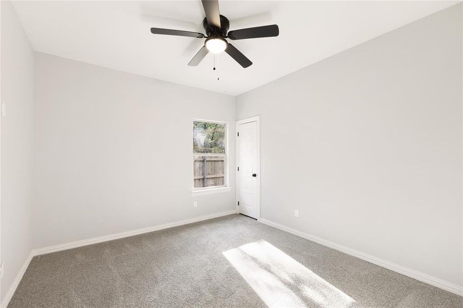 Carpeted spare room with baseboards and a ceiling fan