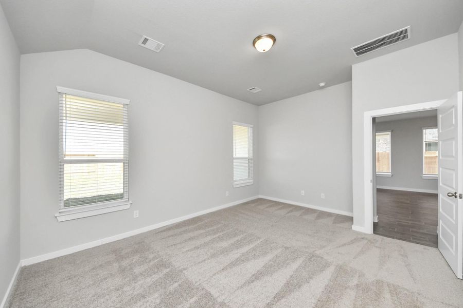 Escape to tranquility in this spacious primary room, adorned with plush carpeting and bathed in the soothing hues of warm paint colors, creating a cozy retreat for relaxation. Sample photo of completed home with similar floor plan. Actual colors and selections may vary.