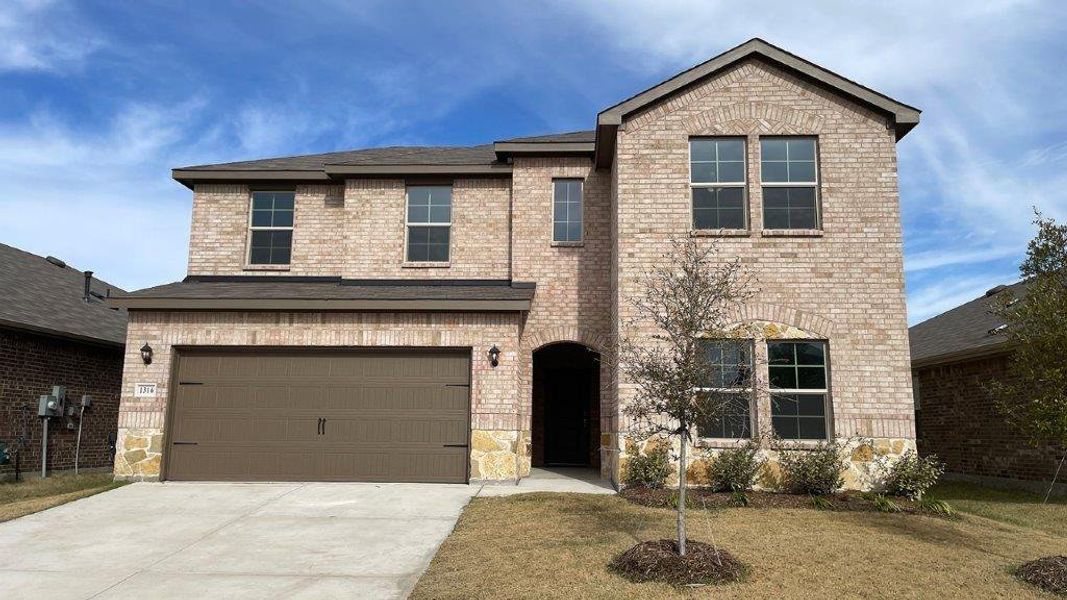 Two-story brick and stone facade residence featuring an arched entry, attached two-car garage, and established landscaping Two-story brick and stone facade residence featuring an arched entry, attached two-car garage, and established landscaping