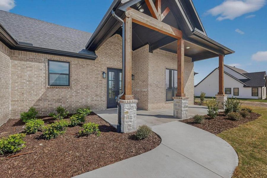 Property entrance featuring brick siding and covered porch