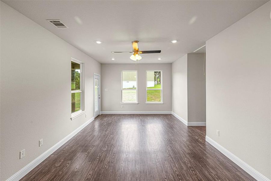 Empty room with ceiling fan and dark hardwood / wood-style flooring