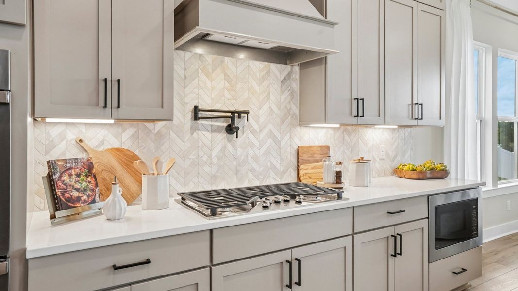 View of kitchen with quartz countertops, tile backsplash, and gas stove-top View of kitchen with quartz countertops, tile backsplash, and gas stove-top