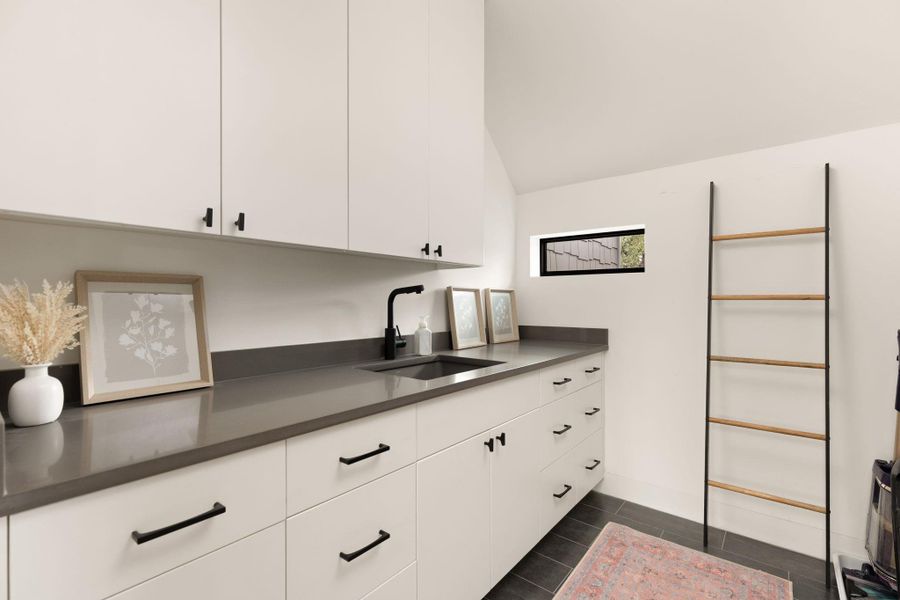 Ample counter space and crisp white cabinetry define this functional and well-appointed utility room. Ample counter space and crisp white cabinetry define this functional and well-appointed utility room.