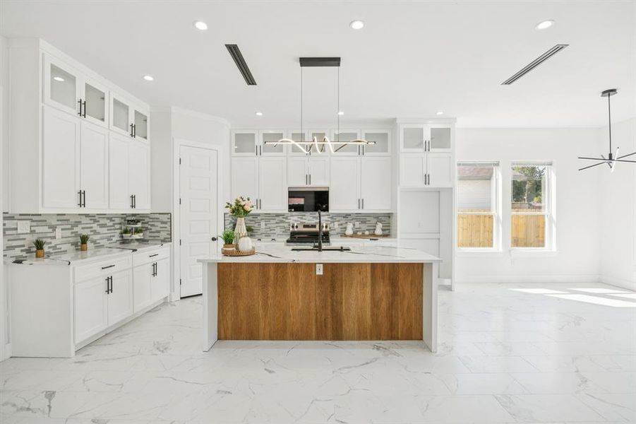 Kitchen with light marble finish floors, glass insert cabinets, light stone counters, white cabinetry, and recessed lighting