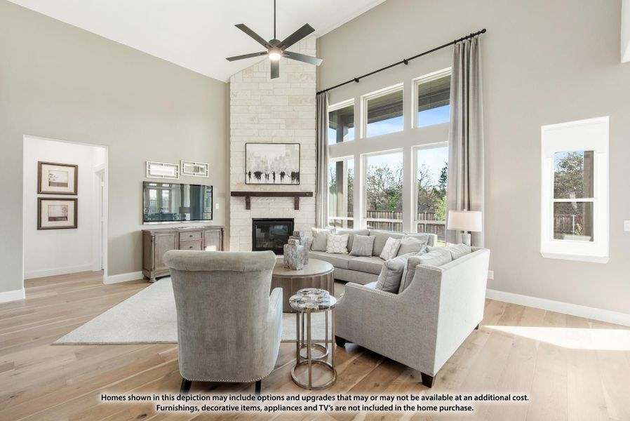 Living room with vaulted ceiling, stone fireplace, hardwood floors, and large windows