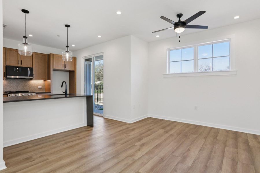 Kitchen featuring decorative light fixtures, stainless steel microwave, light wood-style floors, recessed lighting, and a ceiling fan