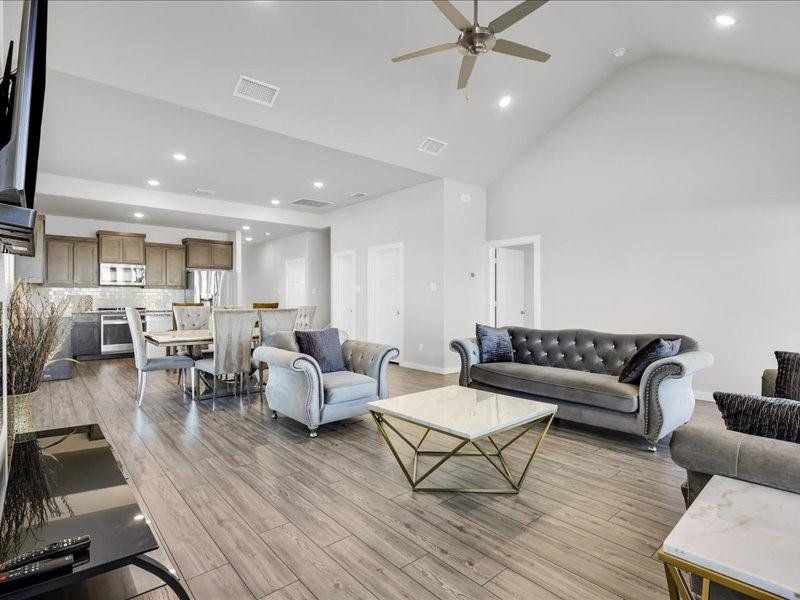 Living room featuring ceiling fan, high vaulted ceiling, and light hardwood / wood-style flooring