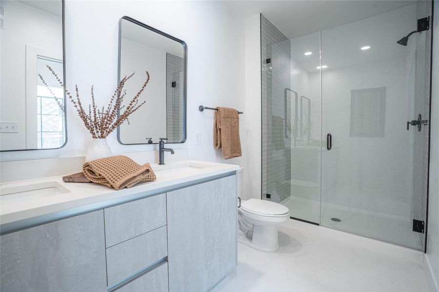 Full bathroom featuring a shower stall, double vanity, and recessed lighting.Photos shown are of a model residence and are representative in nature. Actual residence may differ in layout, finishes, and views.