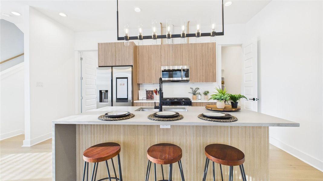 The heart of the second-floor open-concept living, dining, and kitchen, this spacious kitchen island features sleek modern finishes, including a one-sided cascade quartz countertop, a farmhouse sink, and stylish pendant lighting, with a built-in seating area perfect for casual breakfasts or chatting with family and friends.