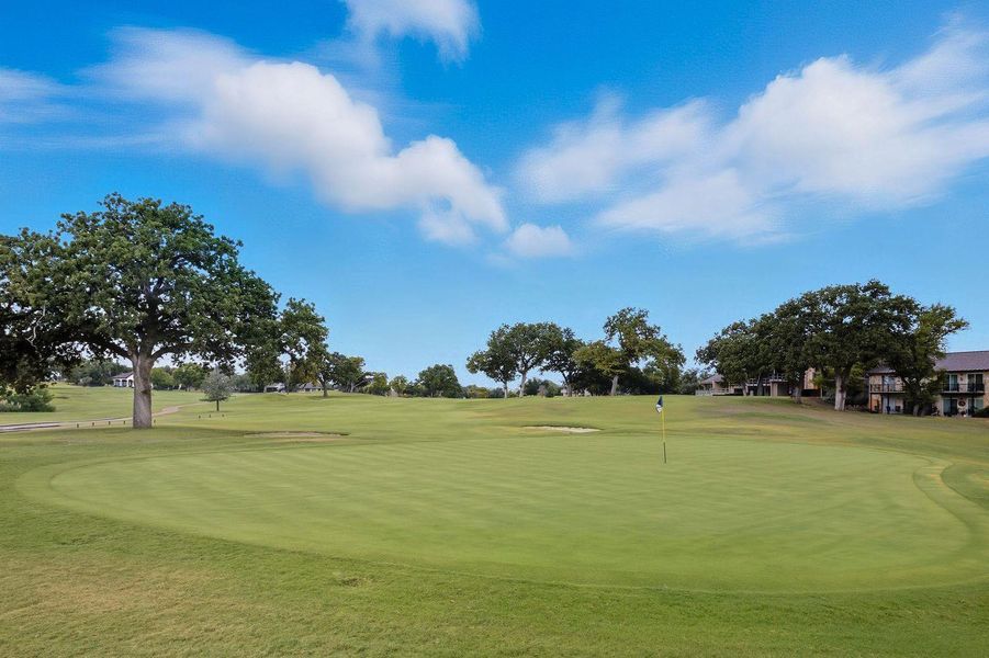 Surrounding community featuring golf course view, a lawn, and a putting green