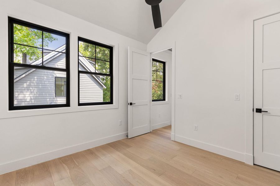 Unfurnished bedroom featuring lofted ceiling, light wood-style flooring, and a ceiling fan Unfurnished bedroom featuring lofted ceiling, light wood-style flooring, and a ceiling fan