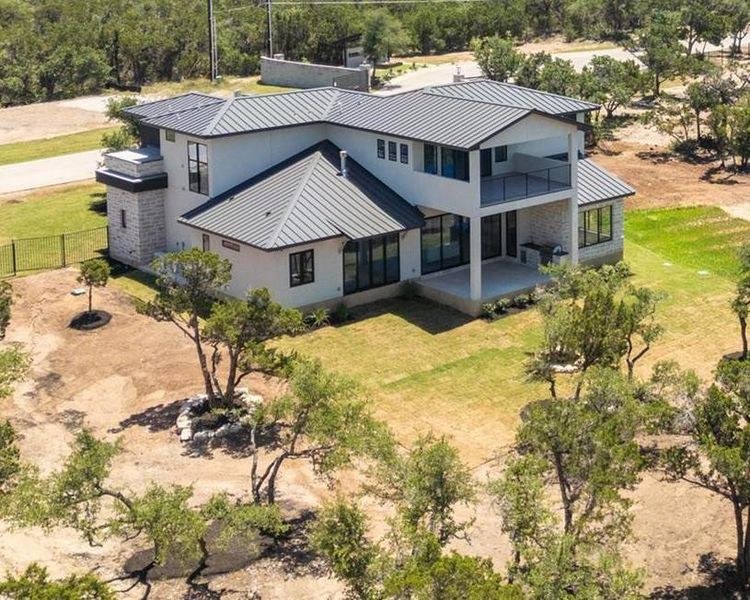 A striking modern home with a metal roof and a spacious balcony overlooking a natural landscape.