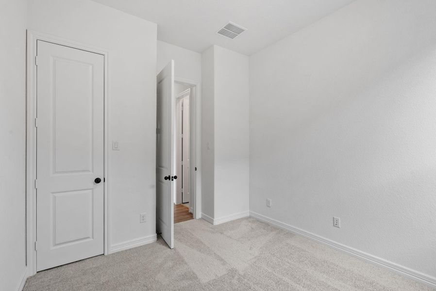 A versatile third bedroom with plush carpet, a window for natural light, and convenient closet storage.