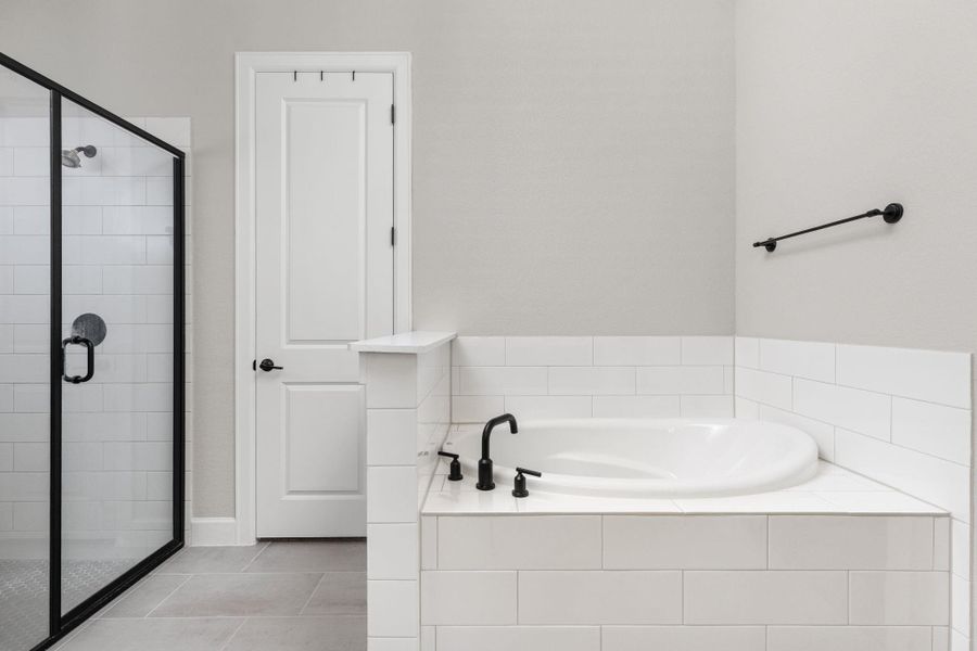 Primary en suite bath featuring a shower stall, a garden tub, and light tile patterned floors