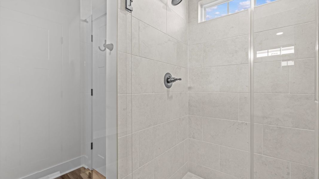 Elegant primary bathroom featuring a spacious tiled walk-in shower and dual vanity in this first-class DRB Homes design