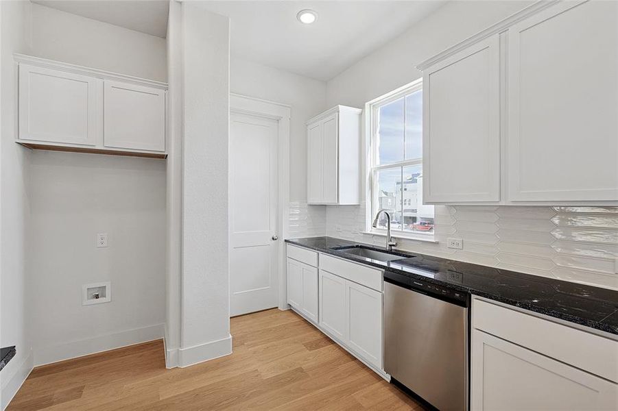 Kitchen with sink, stainless steel dishwasher, tasteful backsplash, and white cabinets Kitchen with sink, stainless steel dishwasher, tasteful backsplash, and white cabinets