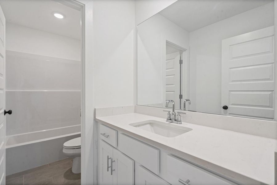 White vanity with an integrated sink, polished chrome faucet, and expansive mirror White vanity with an integrated sink, polished chrome faucet, and expansive mirror