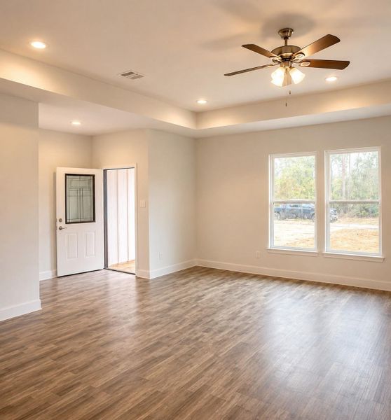 Bright and inviting living space featuring beautiful flooring, recessed lighting, and a ceiling fan, enhanced by natural light from large windows.