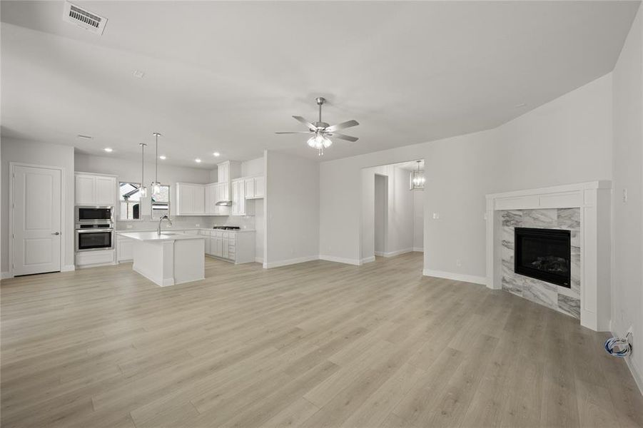 Living room featuring ceiling fan, a fireplace, sink, and light wood-type flooring