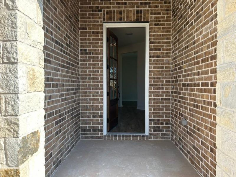 Entrance to property with brick siding and a patio