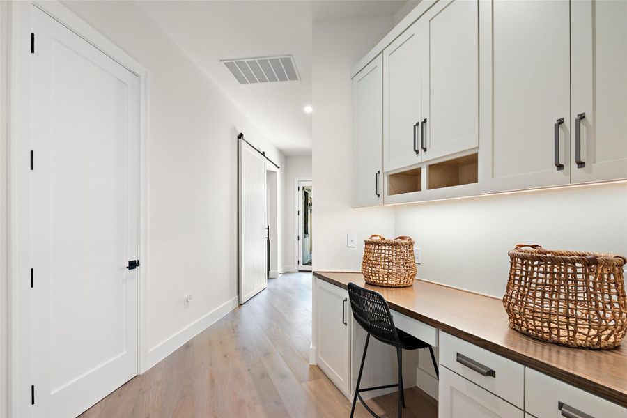 Hallway featuring light wood-style floors, a barn door, and recessed lighting
