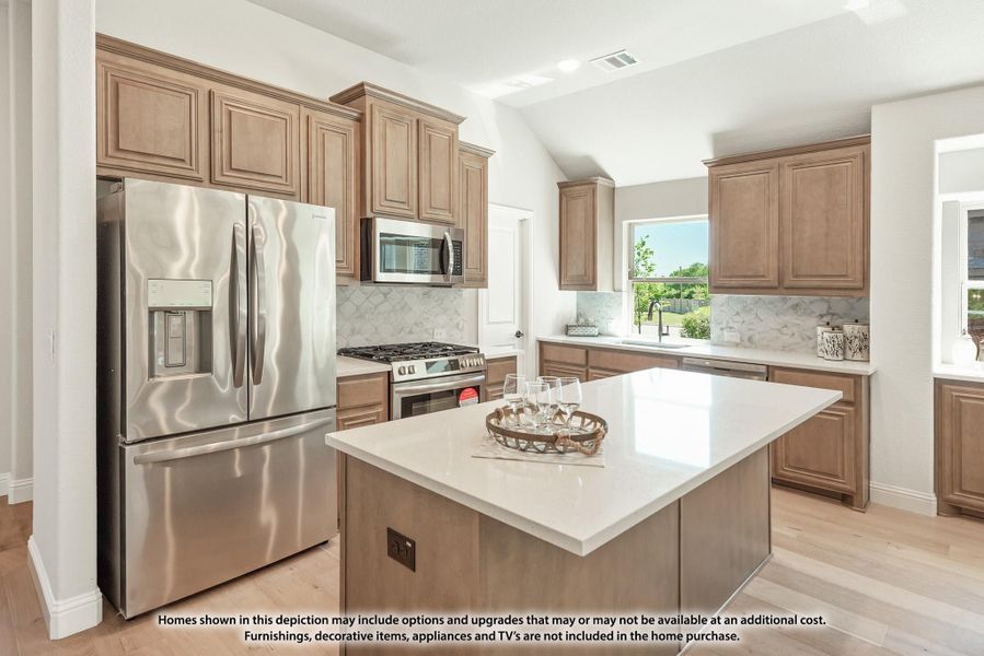 Kitchen with tan wood cabinets, center island, white countertops, and stainless steel appliances on light hardwood floors Kitchen with tan wood cabinets, center island, white countertops, and stainless steel appliances on light hardwood floors