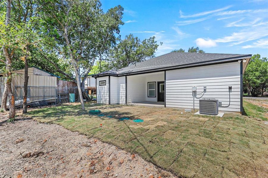 Back of property featuring a lawn, a storage unit, and cooling unit