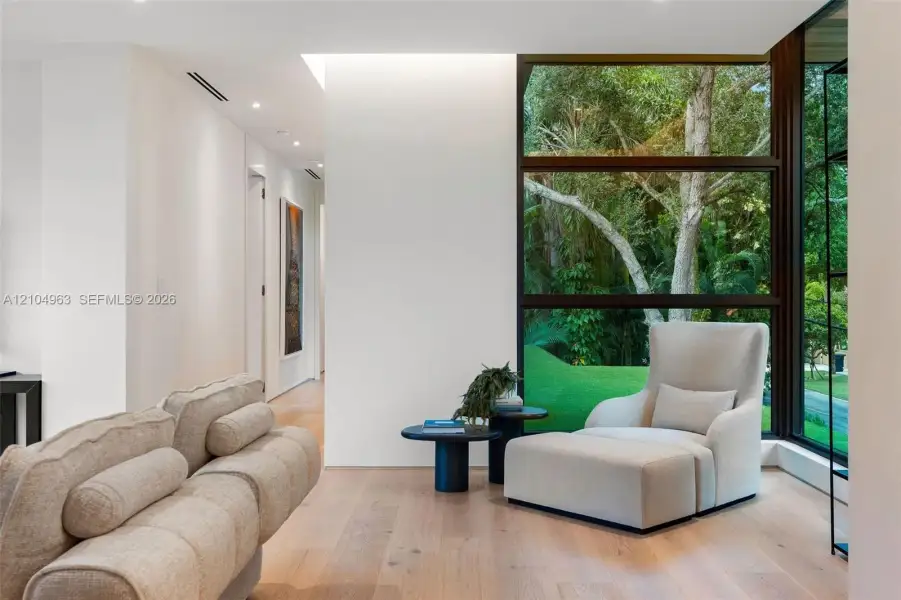 Floor-to-ceiling windows with dark framing, wood-finish flooring, recessed lighting, and minimalist interior architectural design