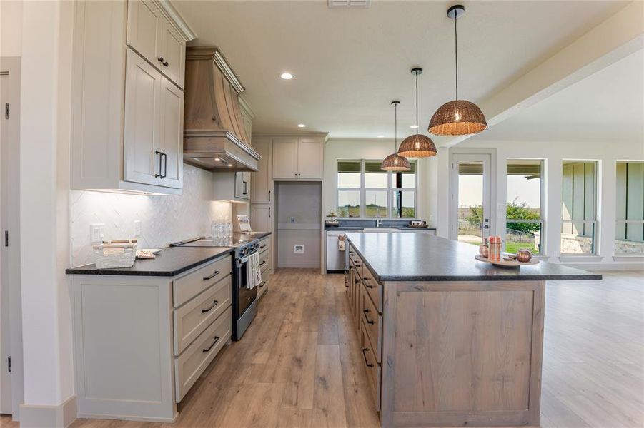 Beautiful backsplash, warm wood tones on the flooring, custom vent-a-hood and painted custom cabinets. Beautiful backsplash, warm wood tones on the flooring, custom vent-a-hood and painted custom cabinets.