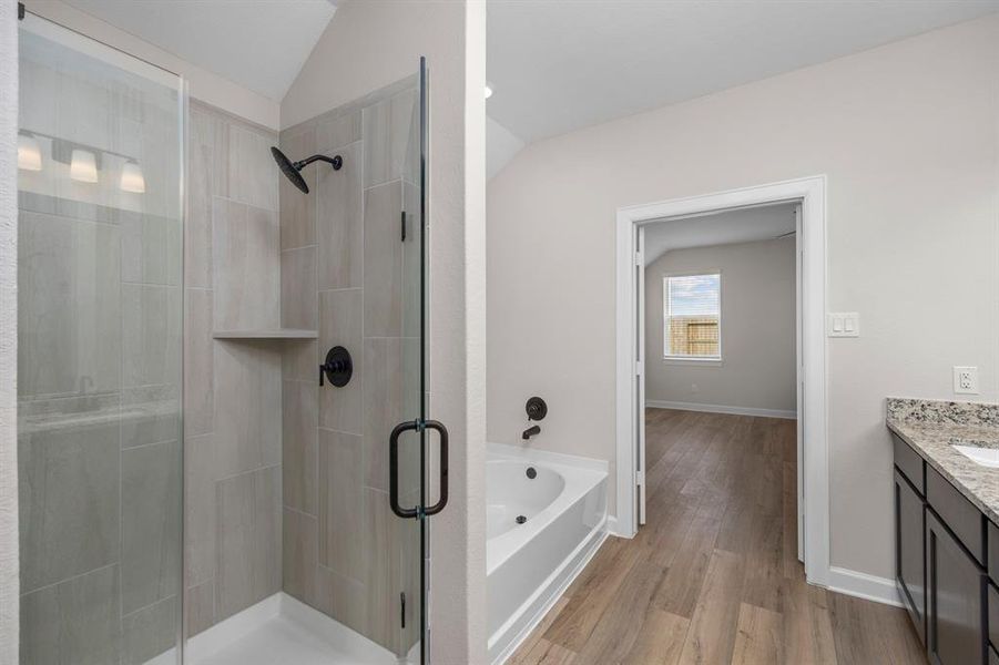 Luxurious en-suite bathroom featuring a sleek glass-enclosed shower, a deep soaking tub, and a granite vanity. The spacious layout connects seamlessly to the master bedroom, creating a private and relaxing retreat.