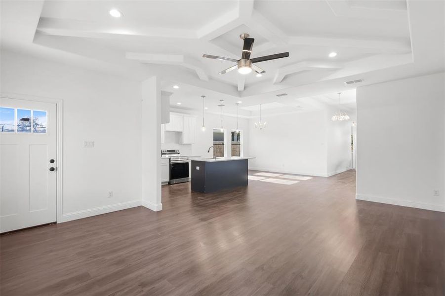 Unfurnished living room with ceiling fan with notable chandelier, beam ceiling, dark hardwood / wood-style flooring, and sink