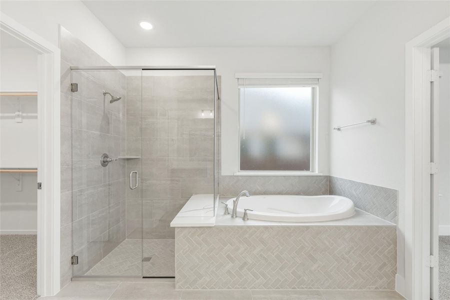 Master bathroom with glass-enclosed tile shower and soaking tub with herringbone tile surround