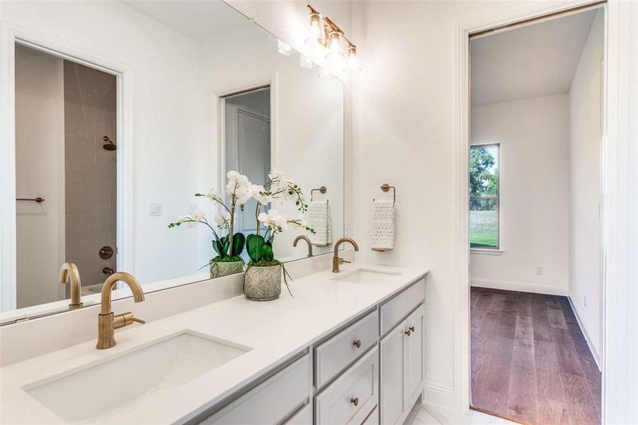 Bathroom with double vanity, a tile shower, and light wood finished floors Bathroom with double vanity, a tile shower, and light wood finished floors