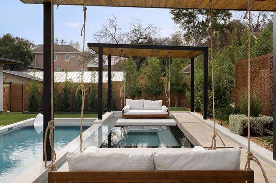 Outdoor living area featuring a swimming pool, integrated spa, and a wood-finish pergola