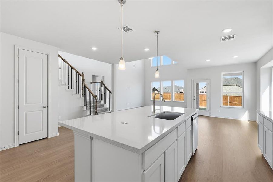 Kitchen featuring light wood-style floors, white cabinetry, hanging light fixtures, a kitchen island with sink, and recessed lighting Kitchen featuring light wood-style floors, white cabinetry, hanging light fixtures, a kitchen island with sink, and recessed lighting