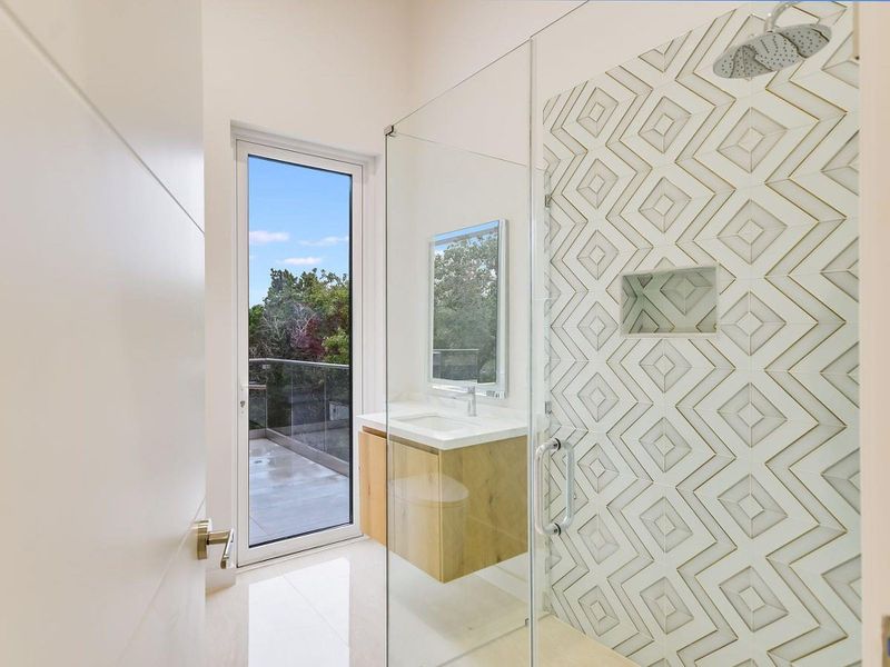 A sleek, contemporary bathroom with a custom tiled shower and a private balcony access. A sleek, contemporary bathroom with a custom tiled shower and a private balcony access.