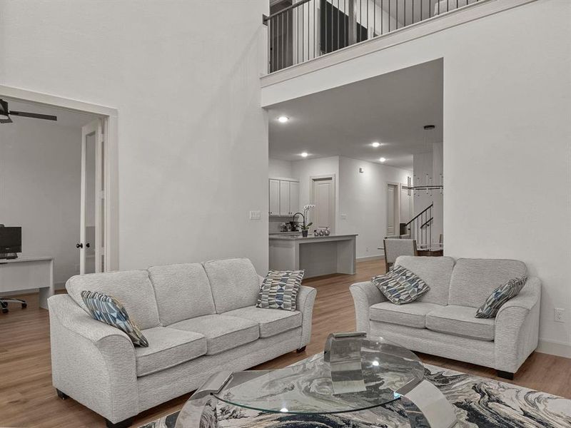 Living room featuring a towering ceiling, light wood-type flooring, ceiling fan, and sink