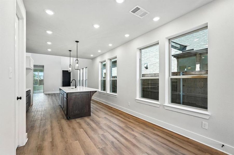 Kitchen featuring decorative light fixtures, an island with sink, white cabinets, recessed lighting, and dark wood-style flooring Kitchen featuring decorative light fixtures, an island with sink, white cabinets, recessed lighting, and dark wood-style flooring