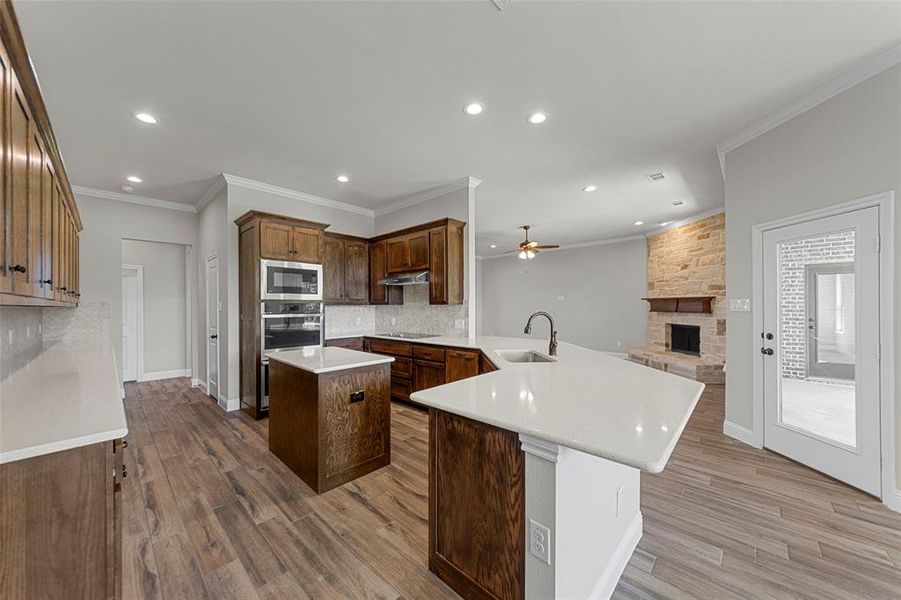 Kitchen featuring built in microwave, a sink, recessed lighting, a kitchen island, and decorative backsplash Kitchen featuring built in microwave, a sink, recessed lighting, a kitchen island, and decorative backsplash