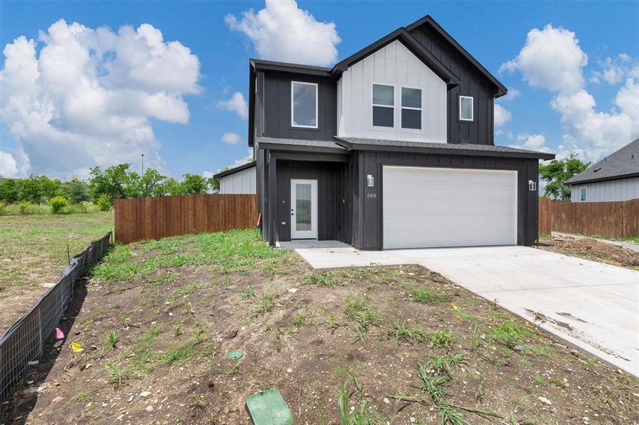 View of front facade with an attached garage, board and batten siding, and driveway