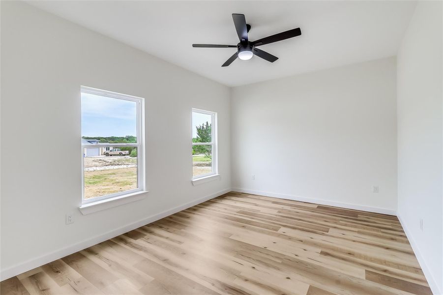 Empty room with light wood-style flooring, baseboards, and ceiling fan