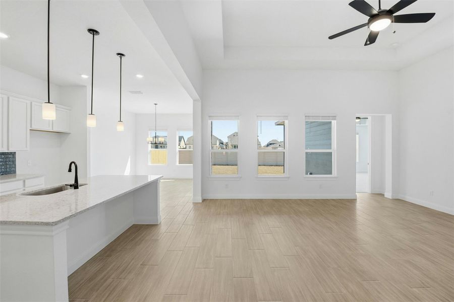 Unfurnished living room with wood tiled floors, ceiling fan, and hanging lights