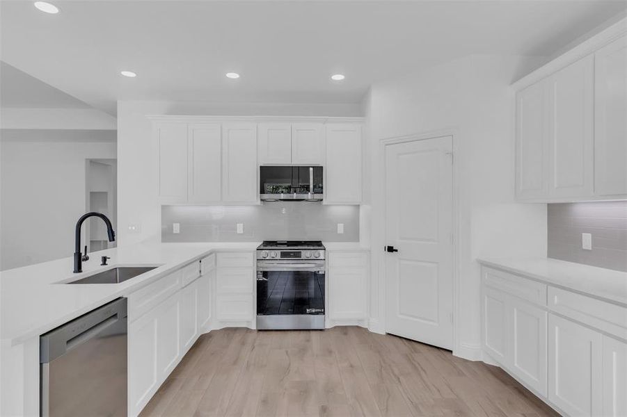 Kitchen with tasteful backsplash, under cabinetry lighting, stainless steel appliances, white cabinetry, a peninsula, and recessed lighting
