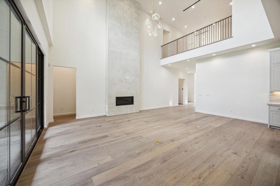 This bright and open living room features a contemporary fireplace and offers a view of the gameroom above, adding character and dimension to the space.