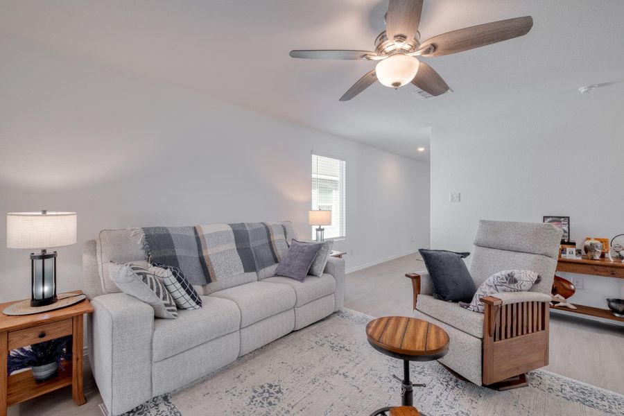 The living area features light-colored walls, a ceiling fan, and light-toned flooring