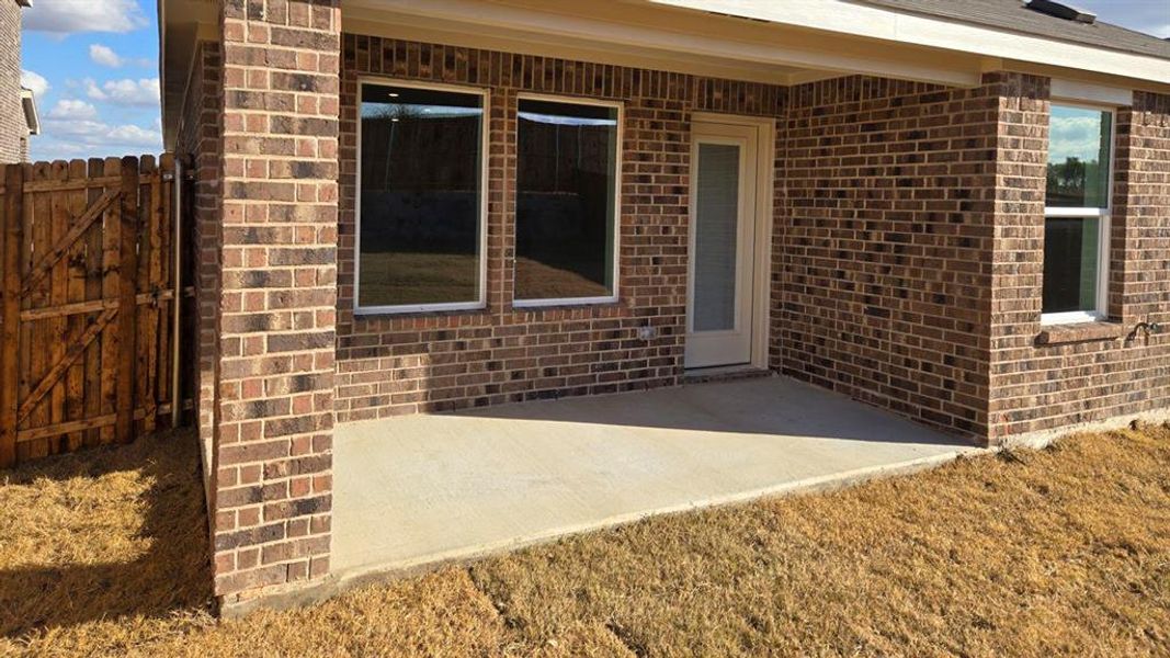 Entrance to property with brick siding and a patio