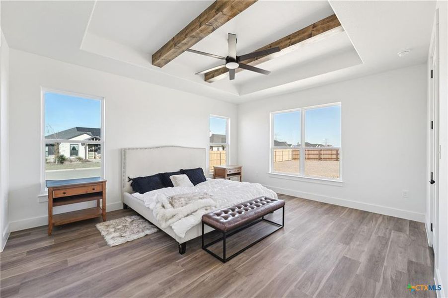 A spacious bedroom presents a striking beamed ceiling with a modern fan and abundant natural light. A spacious bedroom presents a striking beamed ceiling with a modern fan and abundant natural light.