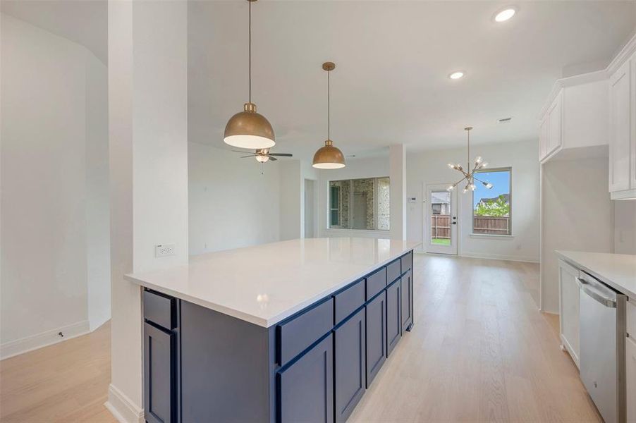 Kitchen island featuring a white countertop and navy cabinetry, complemented by brass pendant lighting